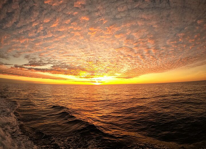 A glorious sunset from a ship on the water with a vast horizon