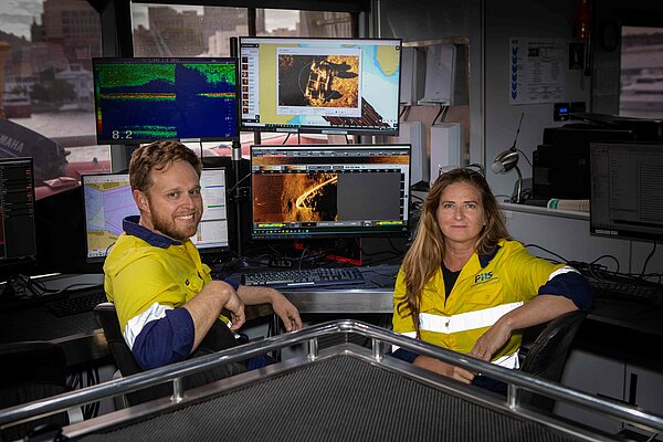 Two Revelare Hydrospatial employees in a work aboard a ship reviewing imaging and mapping data