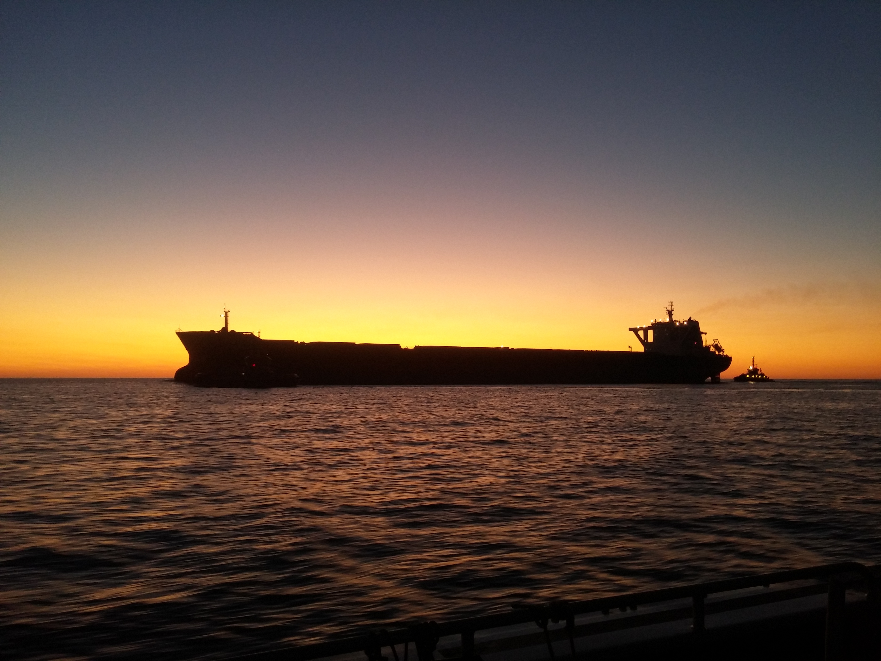 Bulk carrier at sunset during an offshore hydrographic survey project